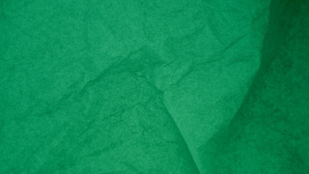 Detailed view of an emerald green wrinkled paper texture for backgrounds or designs.